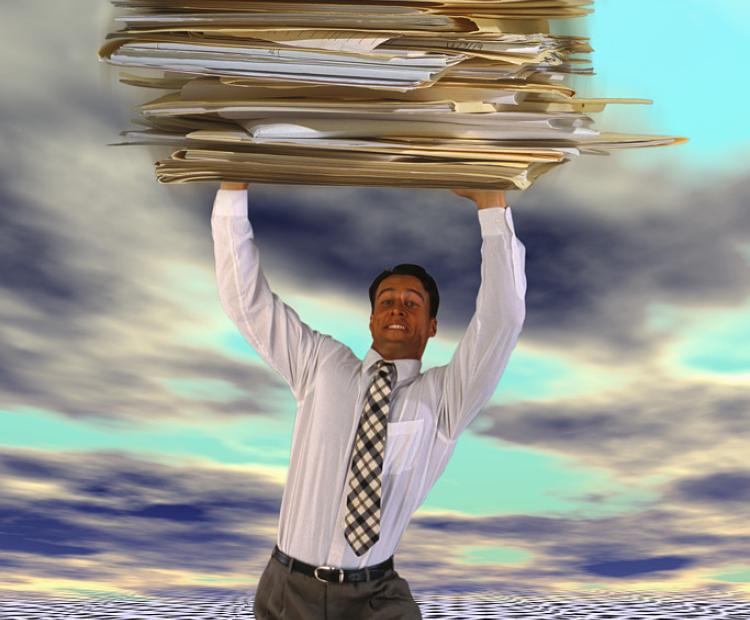 man holding up a big pile of folder and paper